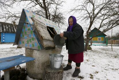 Una mujer llena un cubo con agua de un pozo en Rum, Bielorrusia.