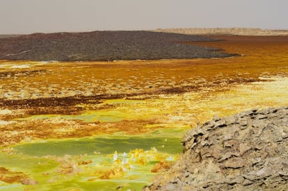 Dallol, situado en <a href="https://elviajero.elpais.com/elviajero/2017/11/15/actualidad/1510743750_163010.html" target="">Etiopía,</a> cerca de la frontera con Eritrea y entre el peligroso y escarpado paisaje de la depresión de Danakil (una inhóspita amalgama de llanuras salinas, volcanes activos y terremotos —en la imagen—), es oficialmente el lugar habitado más caluroso del planeta. La temperatura media anual ronda los 35°C pero en verano el termómetro puede alcanzar los 64°C. Si a ello se le suma la amenaza latente de los rebeldes separatistas de Afar, a nadie le extraña que los lugareños llamen a esta región remota “la puerta del infierno”. Desde Addis Abeba hay que conducir en dirección norte cinco horas y después montar en un camello para recorrer el último tramo por un desierto implacable.