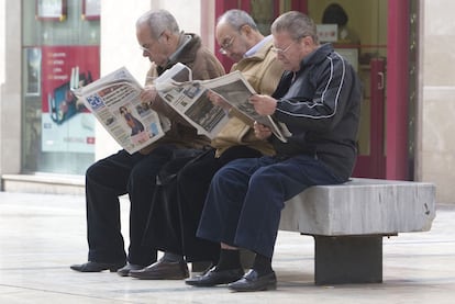 Un grupo de jubilados leyendo la prensa en una calle de Málaga.