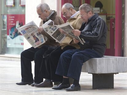 Un grupo de jubilados leyendo la prensa en una calle de Málaga.