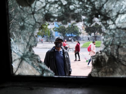 Um homem olha através da janela quebrada de uma delegacia de polícia destroçada logo depois de um protesto em Bogotá, em 5 de maio.