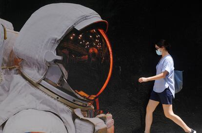 Mulher com máscara de proteção passa por muro pintado em Hong Kong, onde ocorreu caso de reinfecção por covid-19.