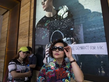 Una mujer frente a una tienda con una pintada prodemocracia el mi&eacute;rcoles en Hong Kong.