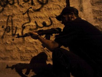 Un rebelde sirio apunta con su arma en una calle de Alepo, este lunes. 