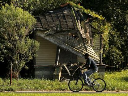 Homem passa diante de casa abandonada no Distrito 9 de Nova Orleans.