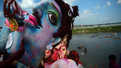 Devotos hindúes cargan con un ídolo que representa a la deidad hindú Ganesha para sumergirla en un estanque temporal cerca de Sangam en Allahabad (India).