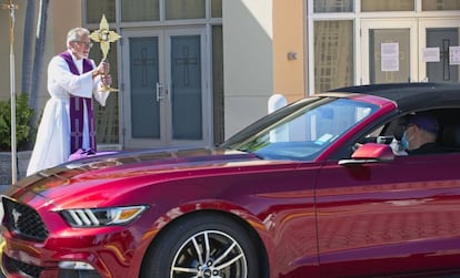 Un sacerdote bendice a un fiel que viaja en coche en Oakland Park (Florida). 