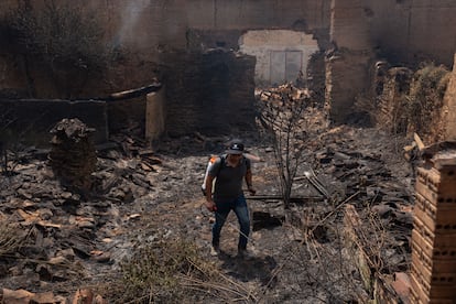 Un vecino de Congosto apaga los rescoldos del incendio que quemó varias casas en la localidad leonesa, este miércoles.