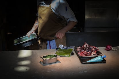 Un chef coloca restos de comida sobre la plancha de la cocina para transformarlos en nuevos platos en el restaurante Tramo de Madrid.