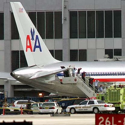 Los pasajeros del vuelo de American Airlines abandonan el avión con las manos en la cabeza.