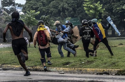 Un grupo de activistas opositores al Gobierno asiste a un manifestante herido durante los enfrentamientos con la policía en una protesta el 24 de junio de 2017.