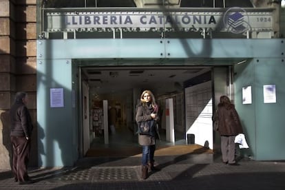 Dos personas leyendo ayer la nota del cierre de la librer&iacute;a Catal&ograve;nia colgada en la puerta.