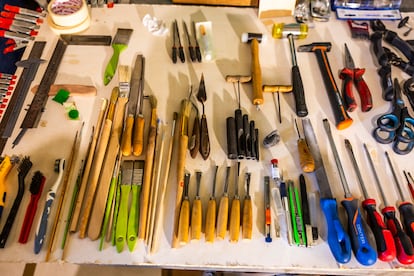 La mesa de Martínez está llena de herramientas que parecen de distintos gremios: cepillos de dientes, martillos, pinceles...