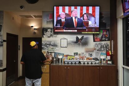 Un trabajador de un restaurante sigue por televisión el discurso del presidente Donald Trump sobre el estado de la Unión.