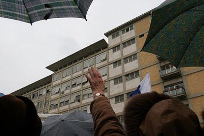 Los fieles se protegen de la lluvia con paraguas ante la clínica donde está internado el Papa.