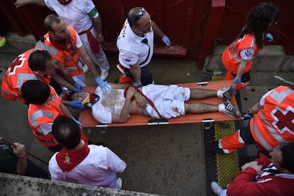 Personal de emergencias transportan a un herido durante el segundo día de encierros de San Fermín.