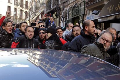 Javier Barbero (derecha) se introduce en un coche mientras es increpado por los asistentes a una concentraci&oacute;n de polic&iacute;as municipales de Madrid.