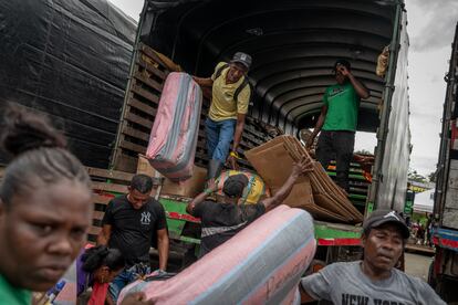 People returning from the community unload their belongings from the trucks.