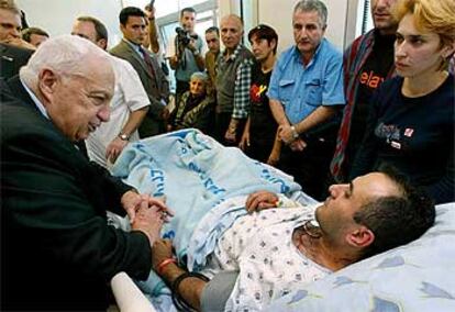 El primer ministro israelí, Ariel Sharon, conversa con uno de los heridos en el atentado de Tel Aviv.