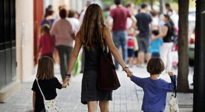 Una madre lleva a sus hijos al colegio.  