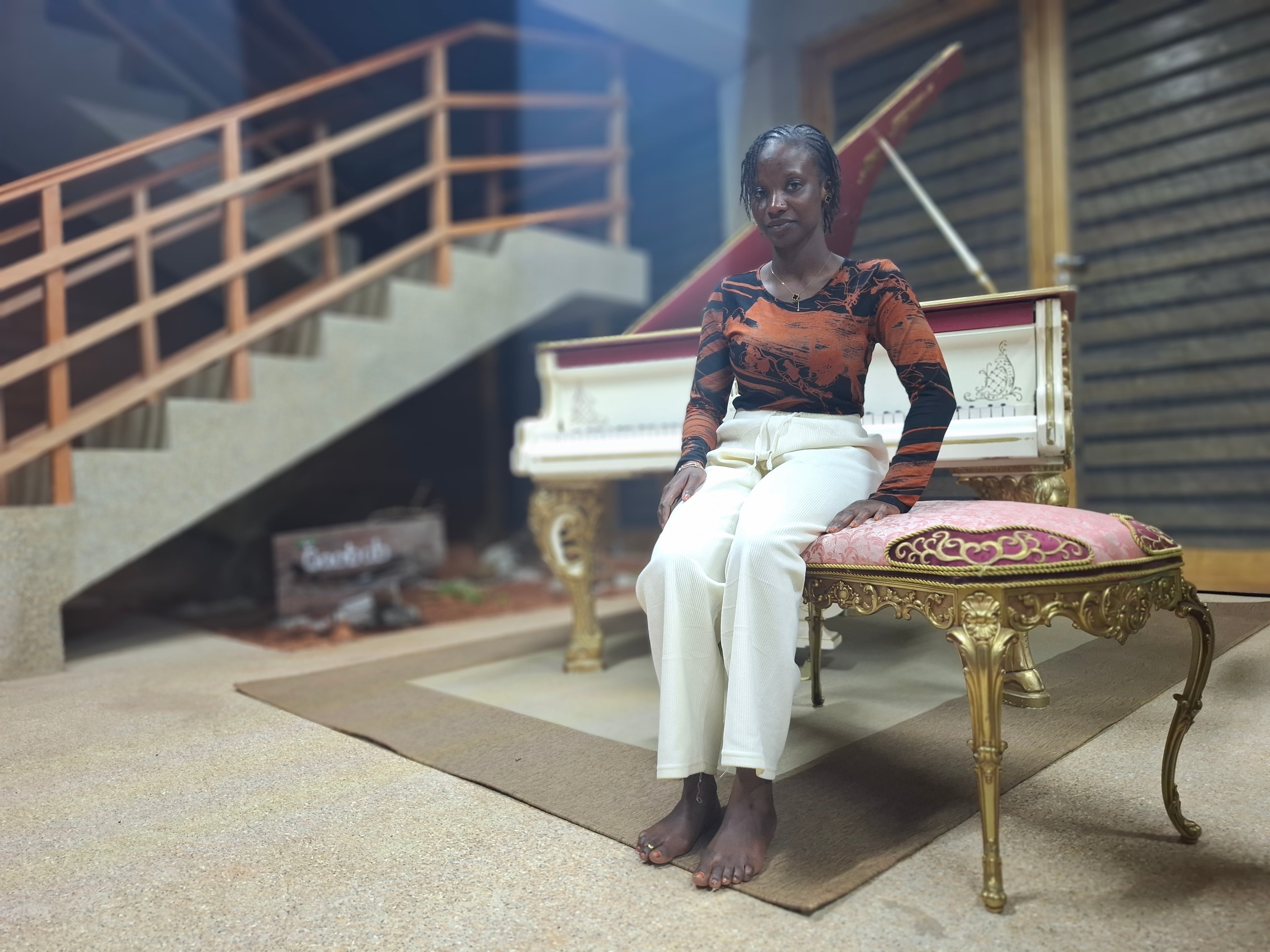 Aicha Gueye, cocinera del hotel escuela Baobab, sentada al piano que decora el salón principal del hotel escuela Baobab.