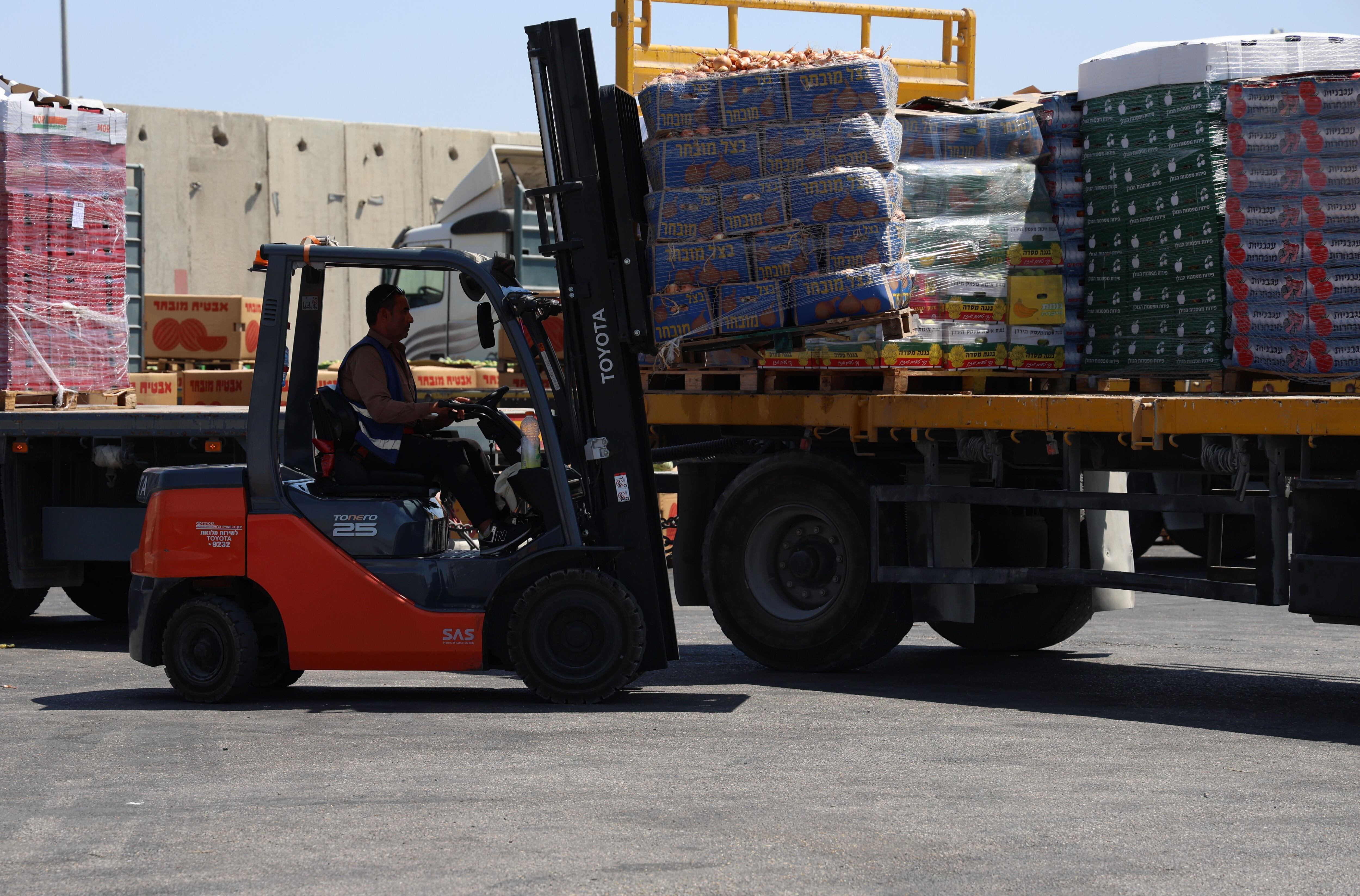 Trabalhadores carregam um caminhão com alimentos para levá-los de Israel a Gaza. 
