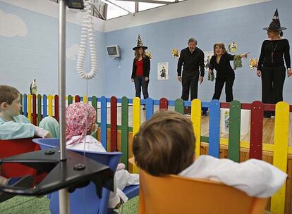 Unos niños presencian la actuación de los <i>cuentacuentos</i> ayer en el hospital de La Paz.