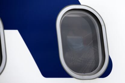 Una pasajera con mascarilla a bordo de un avión.