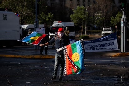 Un hombre lleva banderas mapuches durante la protesta, en el centro de Santiago.
