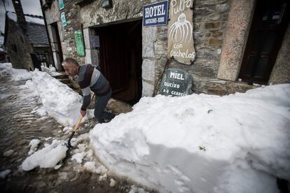 Un vecino se ayuda de una pala para retirar la nieve acumulada en la puerta de un hotel en O Cebreiro, Lugo.