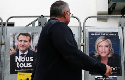 Un peatón camina frente a carteles de la campaña presidencial de Emmanuel Macron y Marine Le Pen