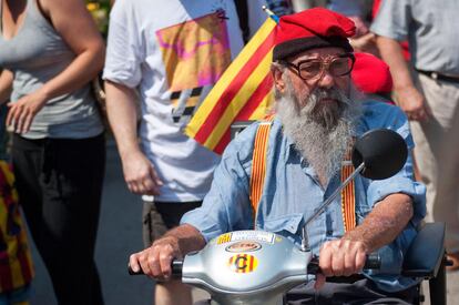 Un home amb barretina i tirants amb la senyera va a votar.