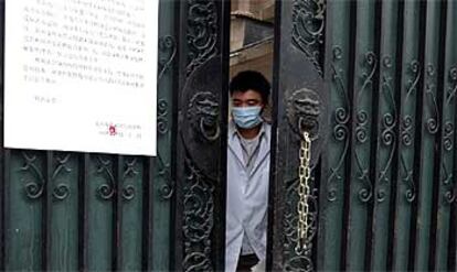 Un empleado con mascarilla abre la puerta del laboratorio de Pekín donde volvió a aparecer el mal hace unos días.