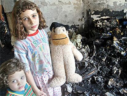 Dos niños iraquíes posan junto a restos de cenizas en su casa de Bagdad, donde cayó un proyectil estadounidense.