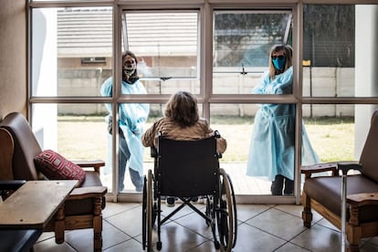 Dos mujeres charlan a través de una ventana con una mujer en silla de ruedas, residente de Casa Serena, un hogar de ancianos en Johannesburgo (Sudáfrica). El país es ahora el quinto del mundo más afectado por la pandemia en número de casos confirmados, más de 408.000.