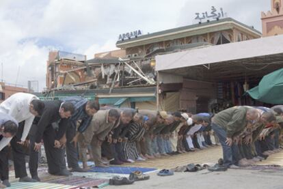 Un grupo de hombres reza ayer ante el café-restaurante Argana, lugar del atentado.