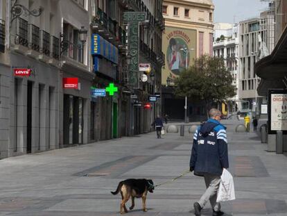Un hombre pasea a su perro por la céntrica calle de Preciados.