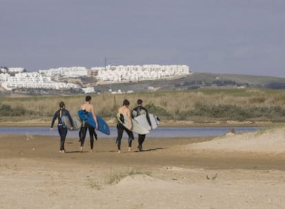 Surfistas pasean frente al paraje de El Palmar donde se proyectan los apartahoteles.