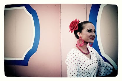 El traje de flamenca, popularmente conocido como traje de gitana, era la indumentaria de faena de las campesinas andaluzas, terminaba por abajo en uno o varios volantes más o menos adornados. En la imagen, una mujer vestida de flamenca, espera en la portada, antes de acceder al recinto ferial.