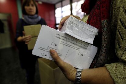 Una voluntària sostè dos paquets de paperetess a un col·legi electoral de Barcelona.