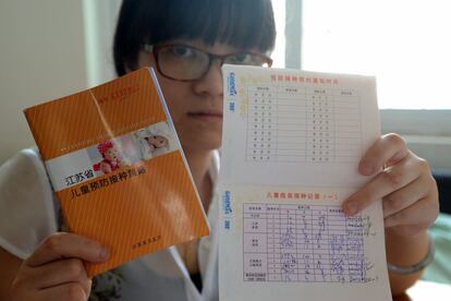 Hu Yen muestra la cartilla del seguimiento médico del embarazo, el parto, y el crecimiento de Jiang Siqi. Y otra con las vacunas que ha recibido la pequeña.