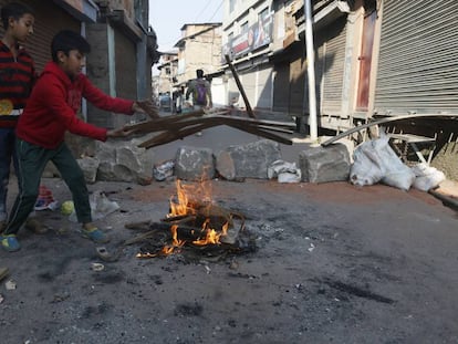 Niños intentan avivar un fuego cerca de una barricada en el centro de Srinagar, la principal ciudad del valle de Cachemira, este jueves. 
 
 