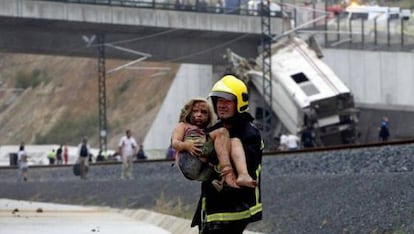 Un bombero carga en brazos a una niña herida.