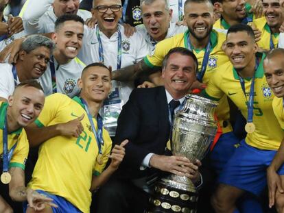 Bolsonaro posa com a taça ao lado dos jogadores da seleção.