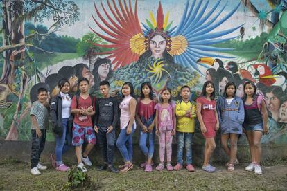 Estudantes indígenas do internato indígena San Francisco de Loretoyaco, em Puerto Nariño (Colômbia), em frente a um mural que conta a história dos clãs da cultura Ticuna em uma das paredes da escola.