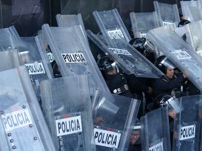 Oficiales de policía se resguardan detrás de un muro de escudos durante los enfrentamientos con manifestantes frente a la sede de la Fiscalía General de la República, en Ciudad de México, el 22 de septiembre de 2022.