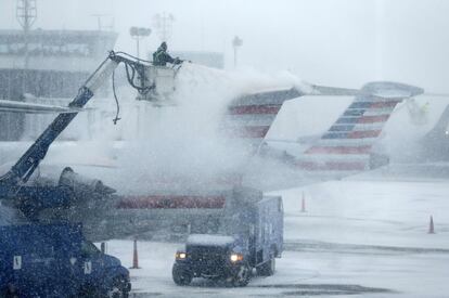 Un trabajador del aeropuerto de La Guardia de Nueva York se afana en descongelar la cola de un avión.