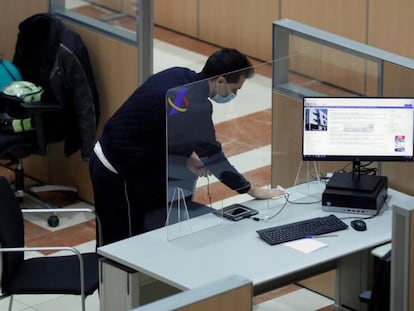 Un hombre desinfecta uno de los puestos dela sede de la delegación de Hacienda de Guzmán el Bueno en Madrid. 