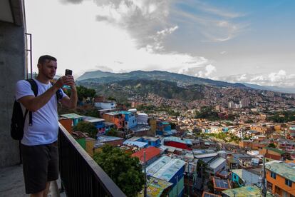 Un turista toma una foto con su móvil desde lo alto de la Comuna 13 de Medellín. Atraer el turismo ha sido clave para los miembros de Casa Kolacho, ya que les permite enseñar a los jóvenes pandilleros que hay vida más allá de la violencia y gente que hace otras cosas.