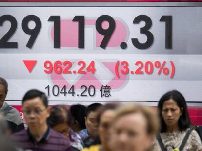 Peatones caminan junto a una pantalla que muestra información bursátil en Hong Kong (China). 